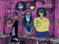 A Muslim woman is walking past a mural painting of faces wearing masks amid a sudden surge of the JN.1 coronavirus in Mumbai, India, on Janu...