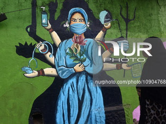 A Muslim woman is walking past a mural painting of a face wearing masks amid a sudden surge of the JN.1 coronavirus in Mumbai, India, on Jan...