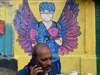 A man is talking on his phone while walking past a mural painting of a doctor wearing masks amid a sudden surge of the JN.1 coronavirus in M...