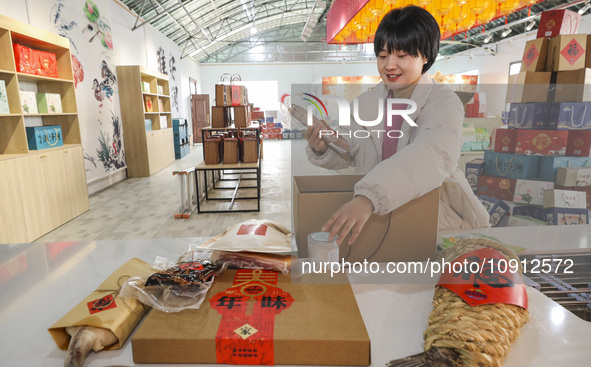 A worker is assembling various kinds of cured meat into gifts and sending them to the market in Huai'an, China, on January 14, 2024. 