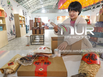 A worker is assembling various kinds of cured meat into gifts and sending them to the market in Huai'an, China, on January 14, 2024. (