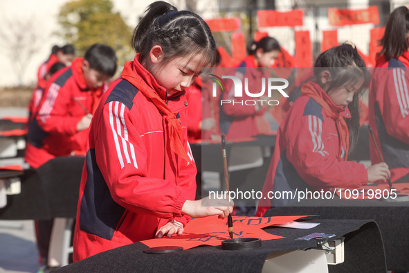 A primary school student is writing a Chinese Spring Festival couplet ''Fu'' at Shangbai Primary School in Deqing County, Huzhou, China, on...