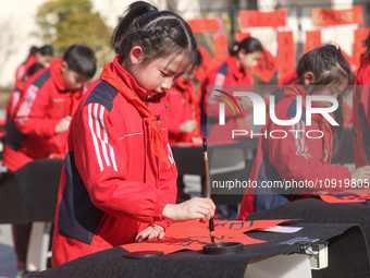 A primary school student is writing a Chinese Spring Festival couplet ''Fu'' at Shangbai Primary School in Deqing County, Huzhou, China, on...