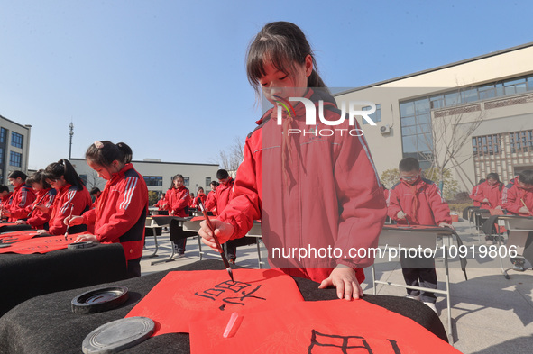 A primary school student is writing a Chinese Spring Festival couplet ''Fu'' at Shangbai Primary School in Deqing County, Huzhou, China, on...