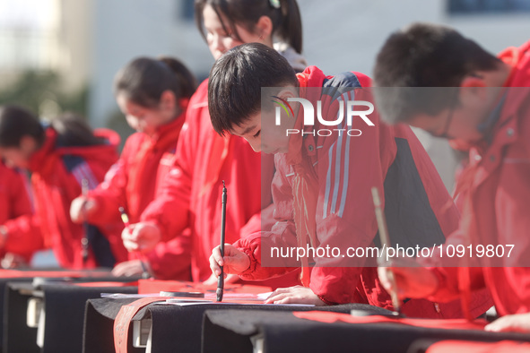 A primary school student is writing a Chinese Spring Festival couplet ''Fu'' at Shangbai Primary School in Deqing County, Huzhou, China, on...