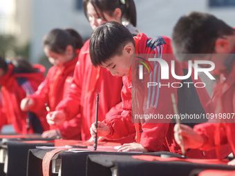 A primary school student is writing a Chinese Spring Festival couplet ''Fu'' at Shangbai Primary School in Deqing County, Huzhou, China, on...