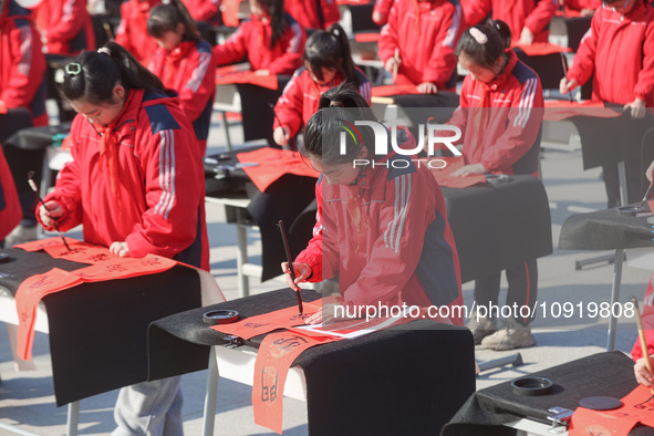 A primary school student is writing a Chinese Spring Festival couplet ''Fu'' at Shangbai Primary School in Deqing County, Huzhou, China, on...