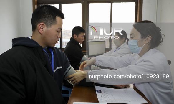 A medical worker is measuring the blood pressure of a young applicant in Huai'an, Jiangsu Province, China, on January 19, 2024. 