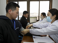 A medical worker is measuring the blood pressure of a young applicant in Huai'an, Jiangsu Province, China, on January 19, 2024. (