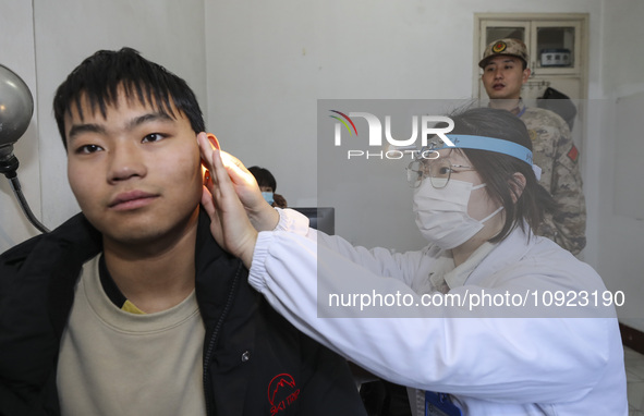 A medical worker is checking the ears of young applicants in Huai'an, Jiangsu Province, China, on January 19, 2024. 