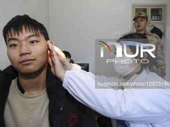 A medical worker is checking the ears of young applicants in Huai'an, Jiangsu Province, China, on January 19, 2024. (