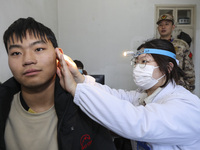 A medical worker is checking the ears of young applicants in Huai'an, Jiangsu Province, China, on January 19, 2024. (