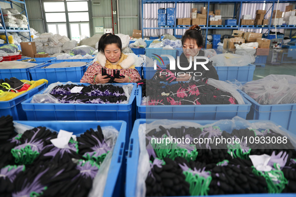 Two workers are producing protective equipment for export at a company in Lianyungang, East China's Jiangsu province, on January 22, 2024. 