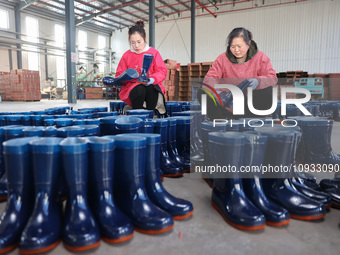 Two workers are producing protective equipment for export at a company in Lianyungang, East China's Jiangsu province, on January 22, 2024. (