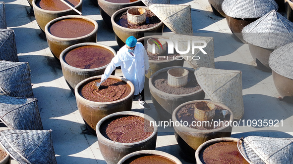 A worker at a soy sauce factory is checking the drying of sauces in a drying field in Lianyungang, China, on January 24, 2024. 