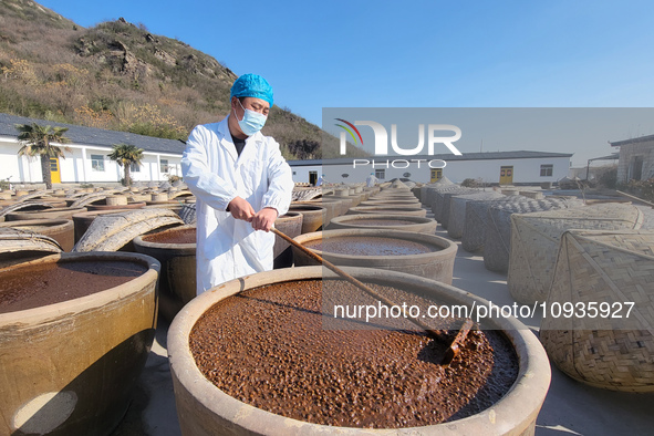 A worker at a soy sauce factory is checking the drying of sauces in a drying field in Lianyungang, China, on January 24, 2024. 