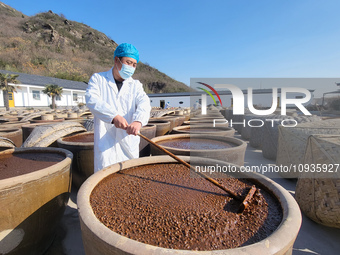 A worker at a soy sauce factory is checking the drying of sauces in a drying field in Lianyungang, China, on January 24, 2024. (