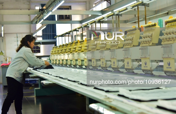 A worker is inspecting products at an automated knitwear assembly line in Nantong, Jiangsu province, China, on January 24, 2024. 