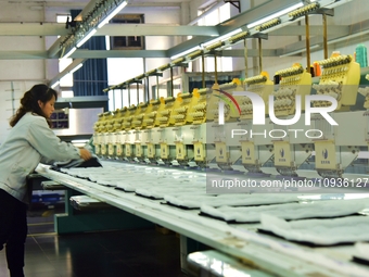 A worker is inspecting products at an automated knitwear assembly line in Nantong, Jiangsu province, China, on January 24, 2024. (