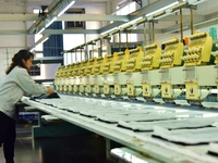 A worker is inspecting products at an automated knitwear assembly line in Nantong, Jiangsu province, China, on January 24, 2024. (