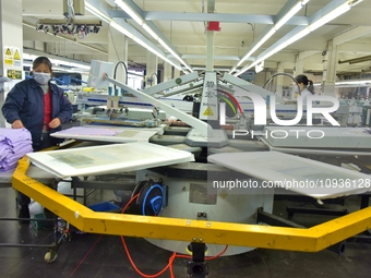 A worker is inspecting products at an automated knitwear assembly line in Nantong, Jiangsu province, China, on January 24, 2024. (