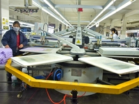 A worker is inspecting products at an automated knitwear assembly line in Nantong, Jiangsu province, China, on January 24, 2024. (