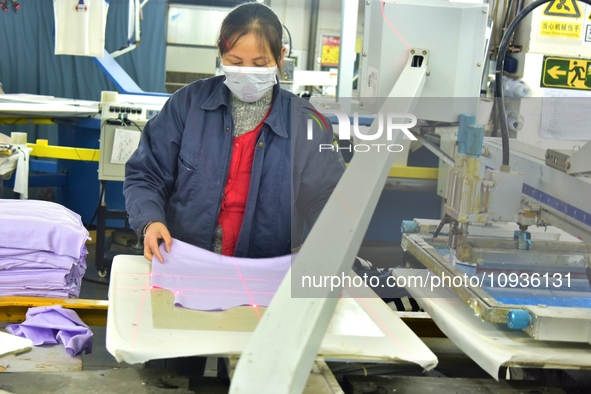 A worker is inspecting products at an automated knitwear assembly line in Nantong, Jiangsu province, China, on January 24, 2024. 