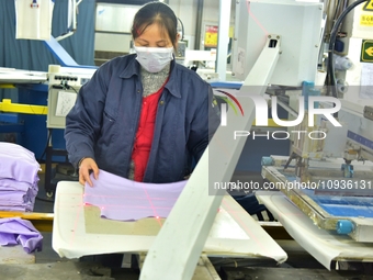 A worker is inspecting products at an automated knitwear assembly line in Nantong, Jiangsu province, China, on January 24, 2024. (