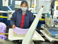 A worker is inspecting products at an automated knitwear assembly line in Nantong, Jiangsu province, China, on January 24, 2024. (