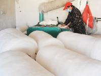 An employee is processing a cotton-padded quilt at a quilt processing shop in Anqing, China, on January 25, 2024. (