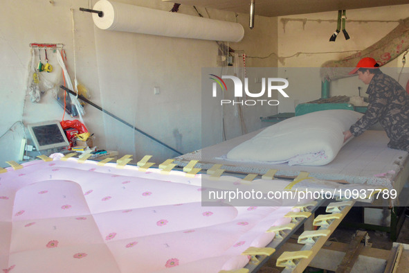 An employee is processing a cotton-padded quilt at a quilt processing shop in Anqing, China, on January 25, 2024. 