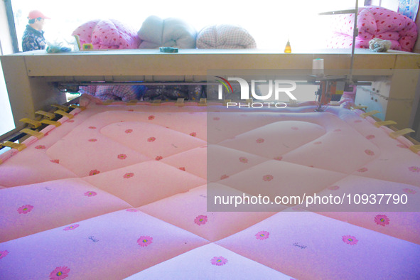 An employee is processing a cotton-padded quilt at a quilt processing shop in Anqing, China, on January 25, 2024. 