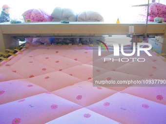 An employee is processing a cotton-padded quilt at a quilt processing shop in Anqing, China, on January 25, 2024. (