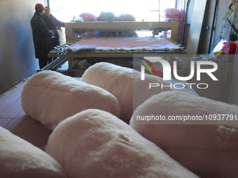 An employee is processing a cotton-padded quilt at a quilt processing shop in Anqing, China, on January 25, 2024. (