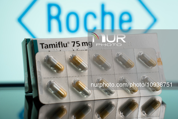 A box and a tablet of Tamiflu pills are being displayed with the Roche Pharmaceuticals logo in the background. 