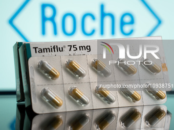 A box and a tablet of Tamiflu pills are being displayed with the Roche Pharmaceuticals logo in the background. (