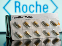 A box and a tablet of Tamiflu pills are being displayed with the Roche Pharmaceuticals logo in the background. (