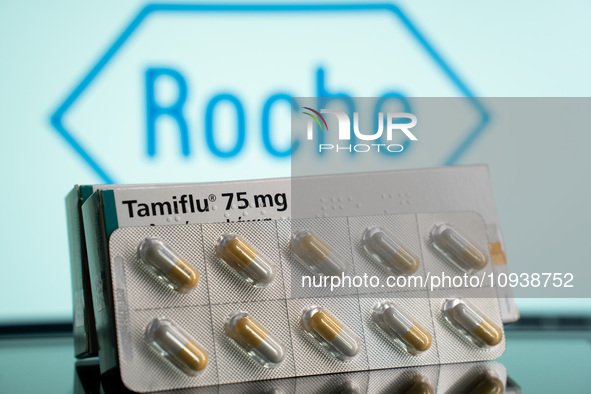 A box and a tablet of Tamiflu pills are being displayed with the Roche Pharmaceuticals logo in the background. 