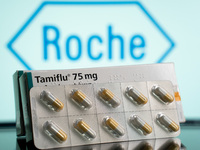 A box and a tablet of Tamiflu pills are being displayed with the Roche Pharmaceuticals logo in the background. (