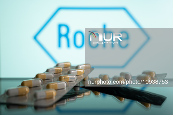 Two tablets of Tamiflu are being displayed with the Roche Pharmaceuticals logo visible in the background. 