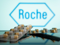 Two tablets of Tamiflu are being displayed with the Roche Pharmaceuticals logo visible in the background. (