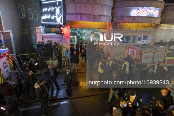 Iranian police officers are monitoring an area while paramedics and firefighters are standing in front of the entrance to the Gandhi hotel h...