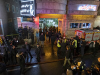 Iranian police officers are monitoring an area while paramedics and firefighters are standing in front of the entrance to the Gandhi hotel h...