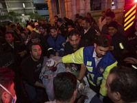 Iranian medical personnel are carrying a patient on a stretcher to an ambulance to transfer him to another hospital during a fire at the Gan...