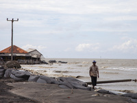 Carmat (83) is walking on the beach near the remains of his house, which was destroyed by high waves in Cemarajaya Village, Karawang Regency...