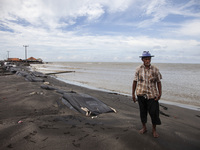 Carmat, 83, is posing for a photo near his house, which was destroyed by high waves in Cemarajaya Village, Karawang Regency, West Java Provi...