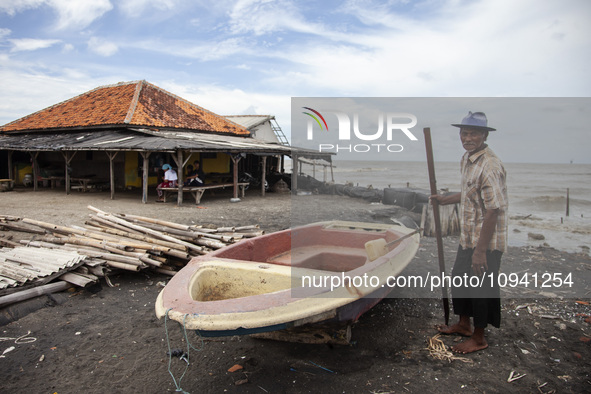 Carmat, 83, is posing for a photo near his house, which was destroyed by high waves in Cemarajaya Village, Karawang Regency, West Java Provi...