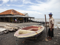 Carmat, 83, is posing for a photo near his house, which was destroyed by high waves in Cemarajaya Village, Karawang Regency, West Java Provi...