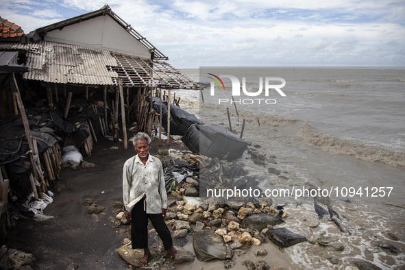 Carmat, 83, is posing for a photo near his house, which was destroyed by high waves in Cemarajaya Village, Karawang Regency, West Java Provi...