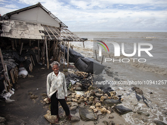 Carmat, 83, is posing for a photo near his house, which was destroyed by high waves in Cemarajaya Village, Karawang Regency, West Java Provi...